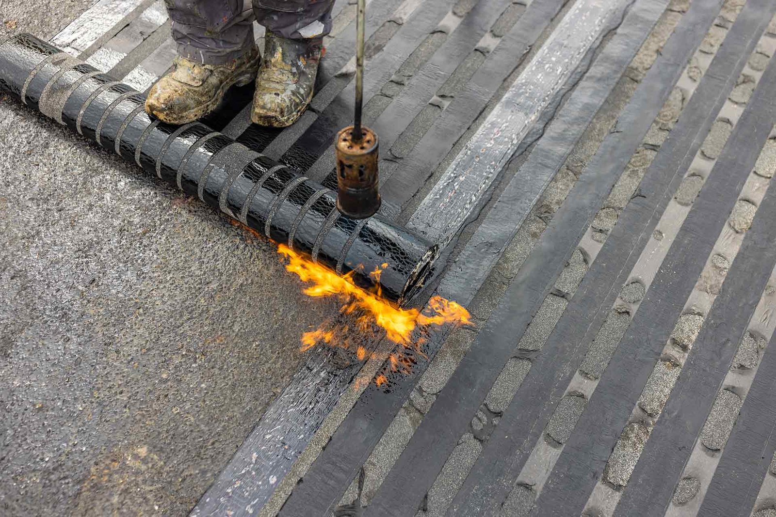 Bitumen dakbedekking wordt in banen aangebracht op een plat dak